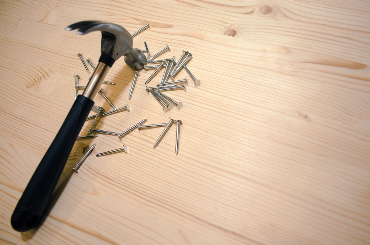 Home construction background. Hammer on wooden table with nails.Repair concept.